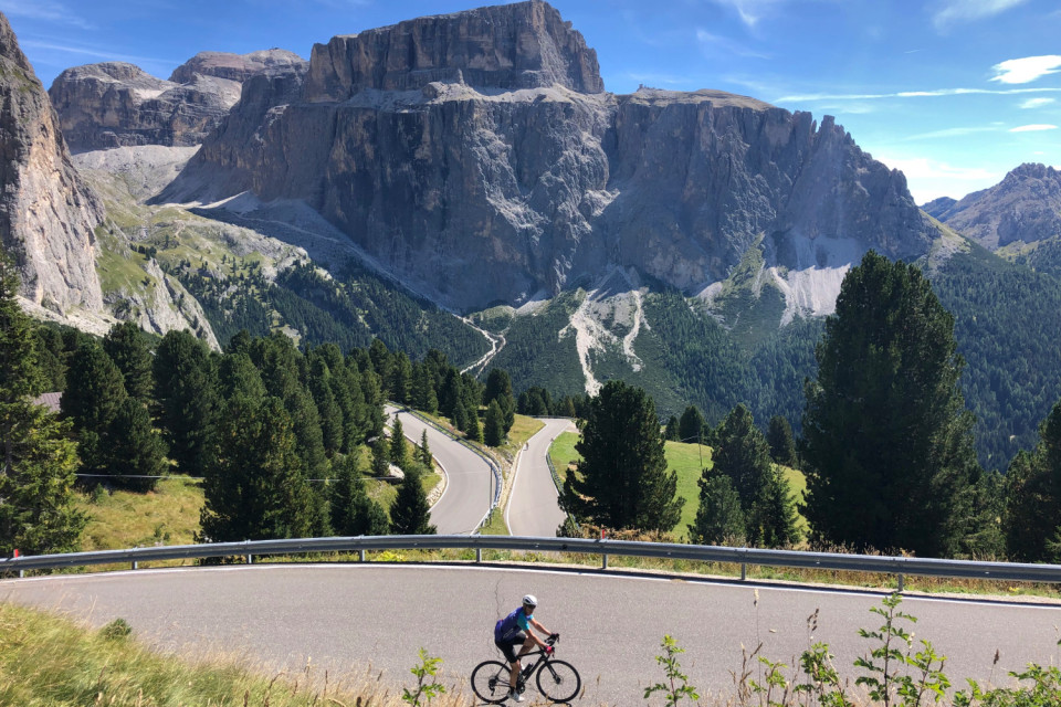 cyclist climbing passo sella in Italian dolomites with towering peaks backdrop on marmot tours guided road bike vacation