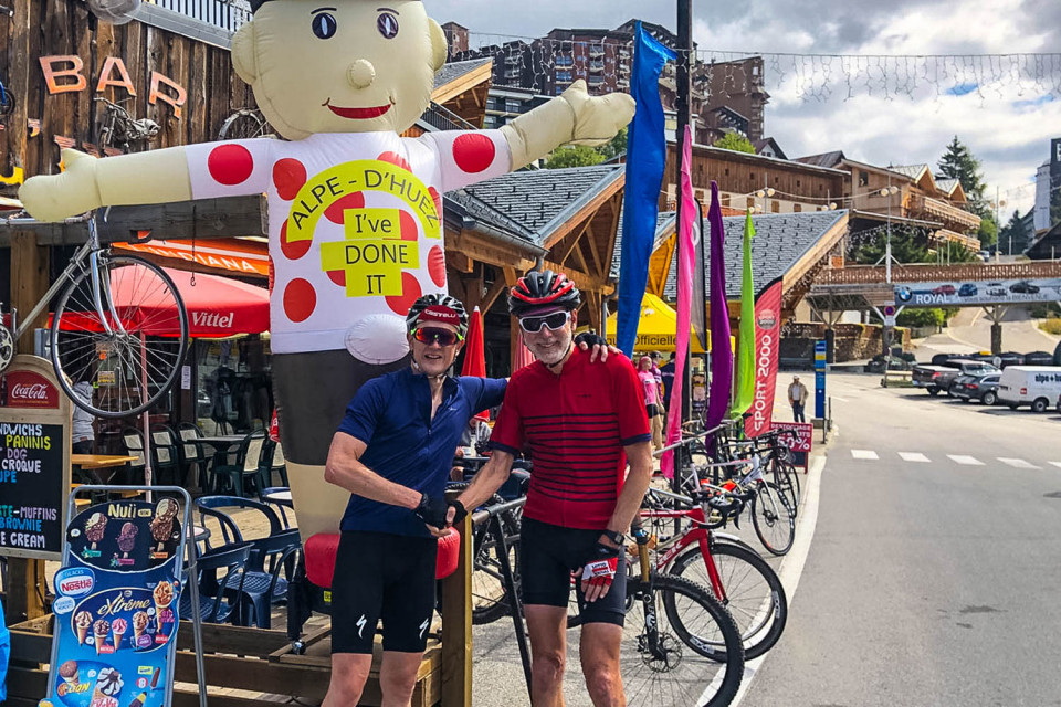 Pair of cyclists celebrating at Alpe d'Huez cycling climb on Marmot Tours guided road cycling holiday Alps