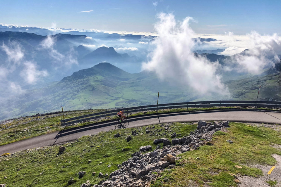 cyclist climbing alto de gamoniteiro with wide view of mountain peaks below in picos mountains asturias northern Spain cycling holiday with marmot tours