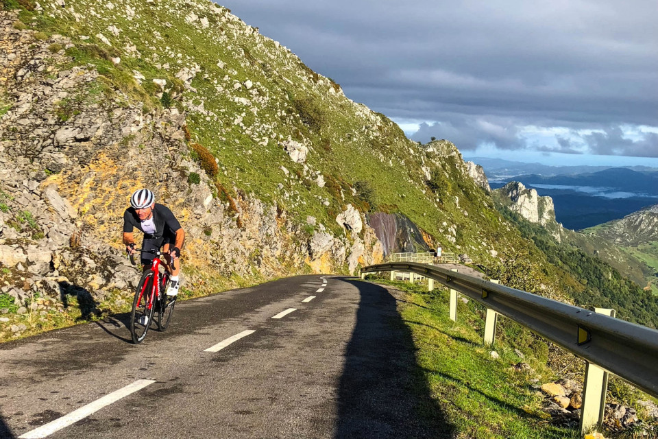cyclist climbing alto de l'angliru asturias mountains with plateau belo on marmot tours guided road cycling holiday northern Spain