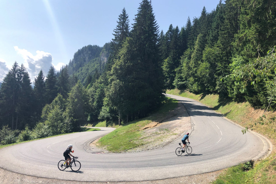 Pair of cyclists climbing hairpin bend on Col de Saisies climb with Marmot Tours guided road cycling holidays Northern French Alps