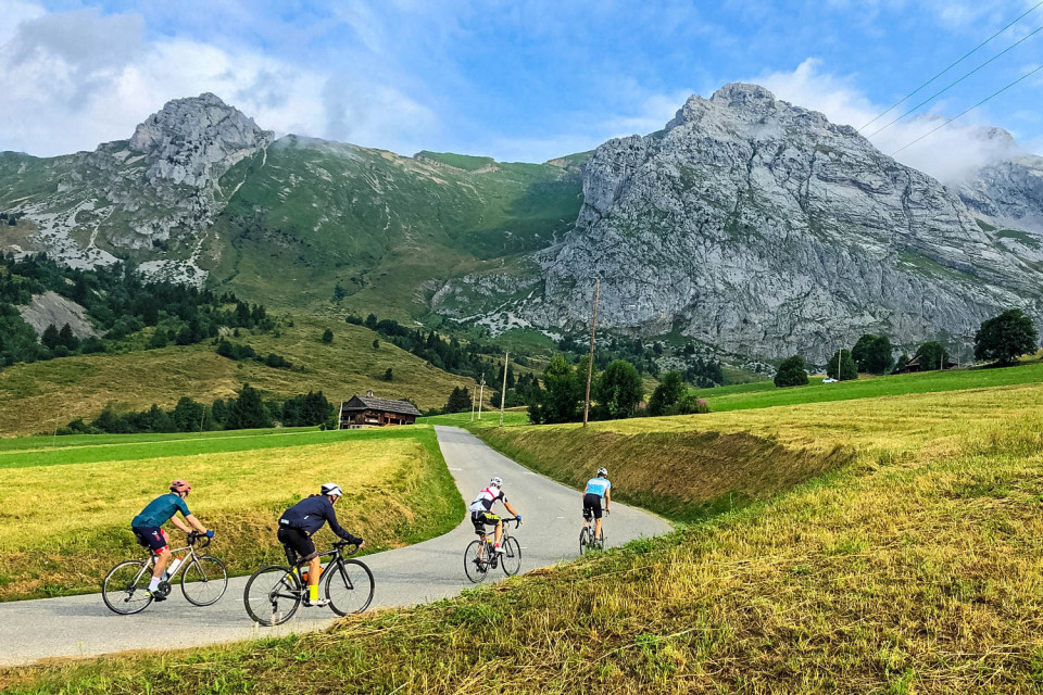 Group of cyclists and rocky peaks on Colombiere cycling climb with Marmot Tours guided road cycling holidays French Alps