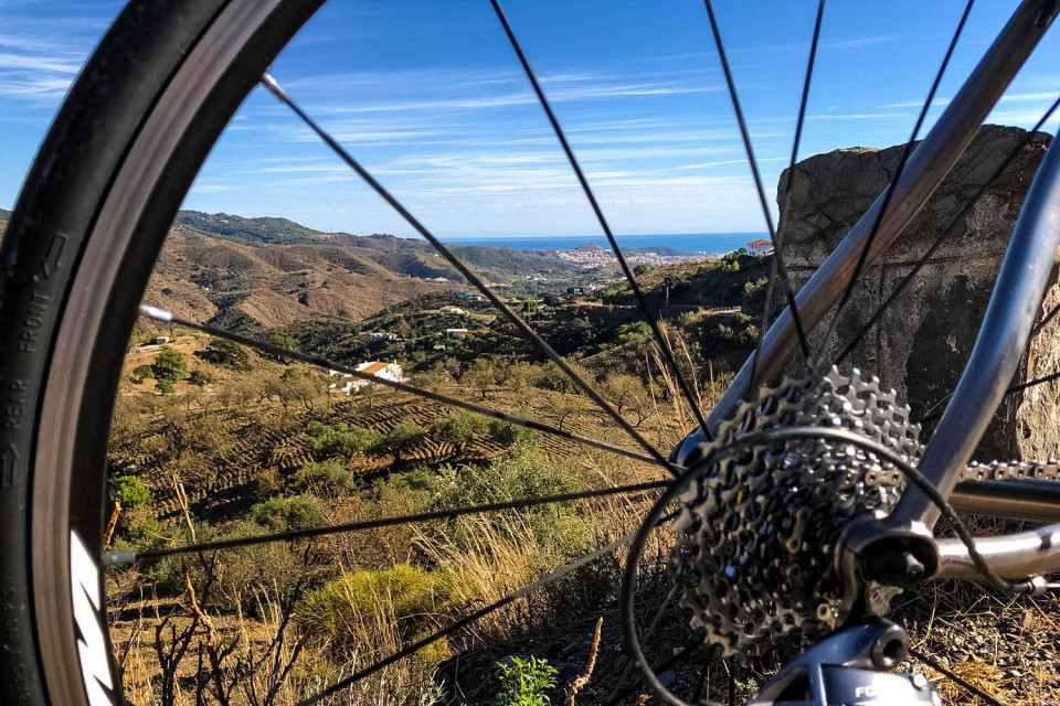View of rolling hills and sea through bicycle spokes on Marmot Tours guided road cycling holiday Andalusia Spain