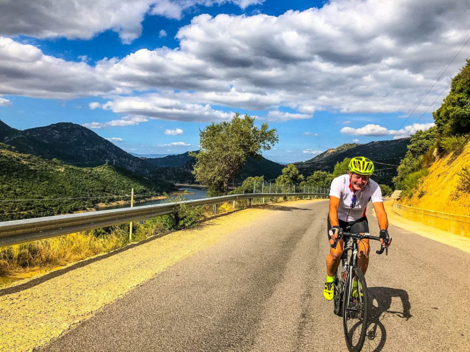 Cyclist smiling on climb with Marmot Tours guided cycling holiday on Corsica