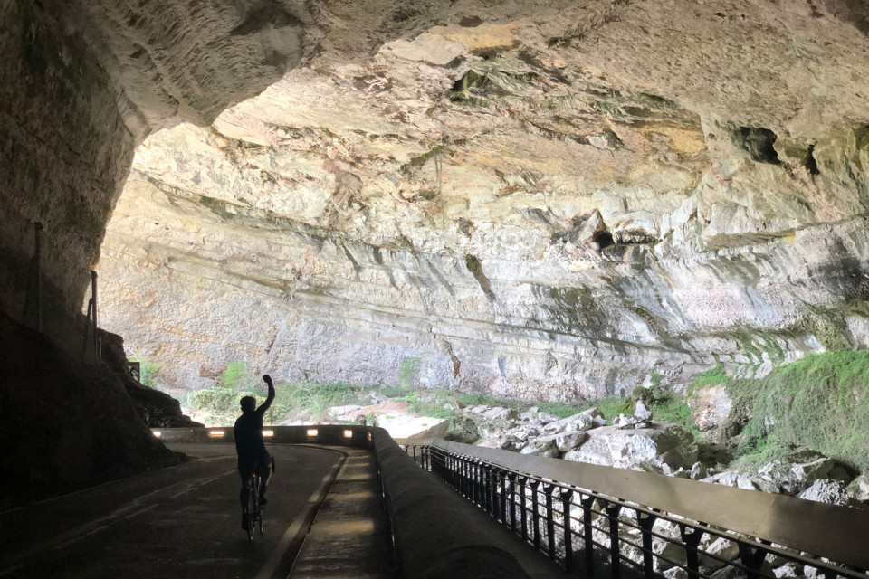 Cyclist air punching riding through cave on Marmot Tours guided tour of Foothills Pyrenees