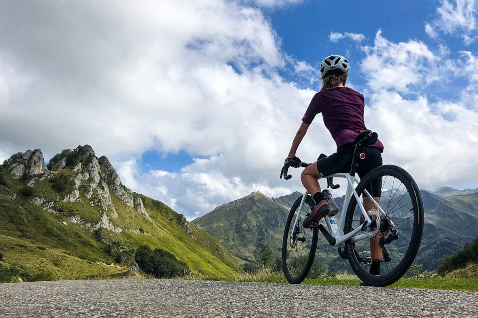 Female cyclist pauses to admire view of French Pyrenees on guided cycling holiday with Marmot Tours