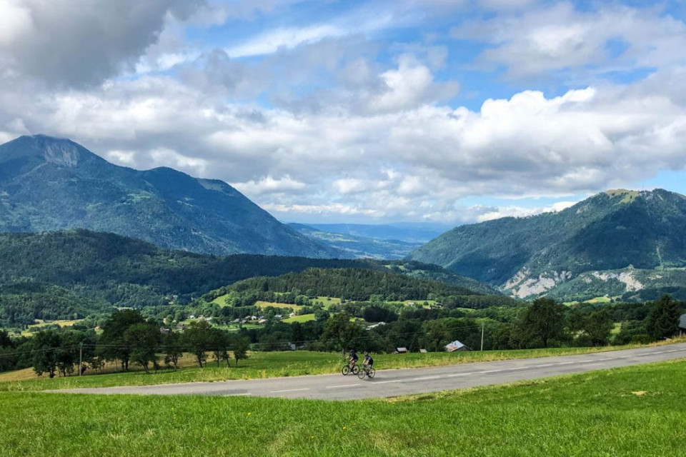 Cyclist and northern French Alps meadow on fully supported road cycling holiday in French Alps with Marmot Tours