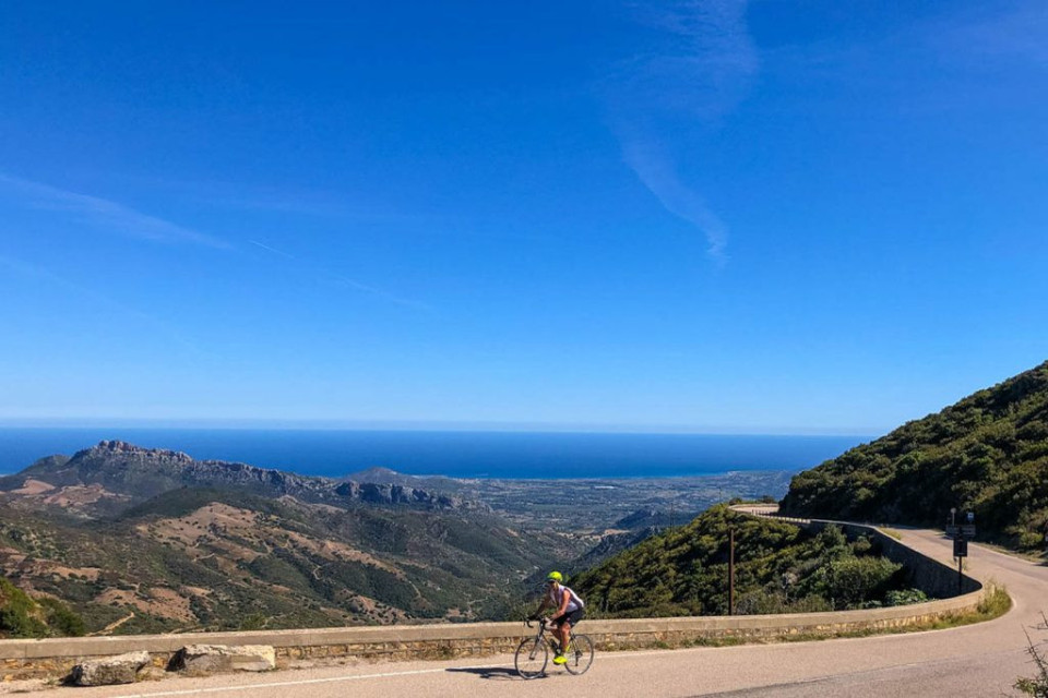 Cyclist enjoying coast road cycling in Sardinia with full support from Marmot Tours