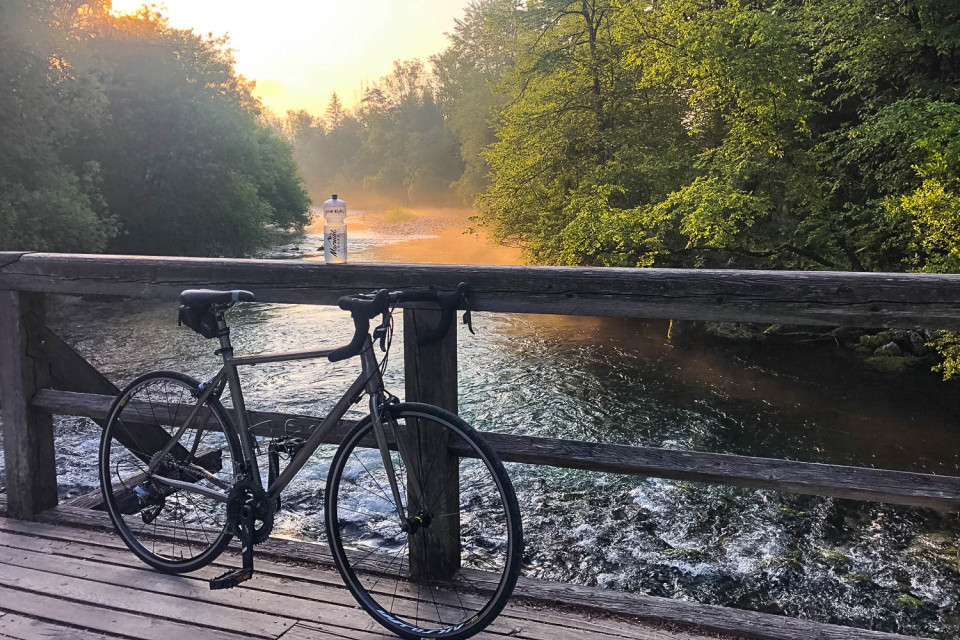 Bicycle on bridge over river at sunset in Slovenia on Marmot Tours guided road cycling holiday
