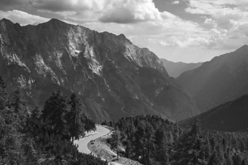 Black and white image of road through forests and mountains on Marmot Tours guided road cycling tour Triglav National Park Slovenia