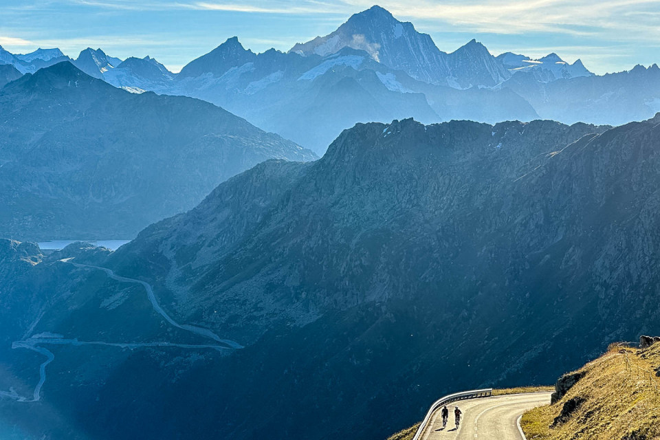 Pair of cyclists and mountain vista of Swiss Alps on Marmot Tours guided road cycling holiday