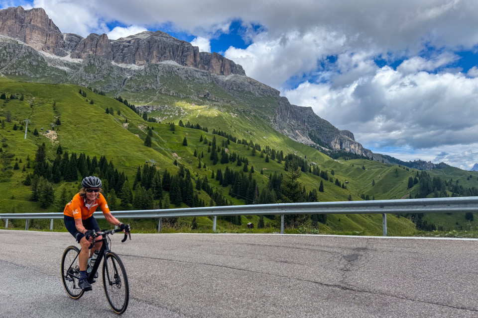 female cyclists climbing dolomites pass with limestone mountains backdrop on marmot tours road bike holiday