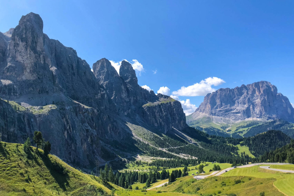 dolomites limestone peaks with mountain road snaking through pastures