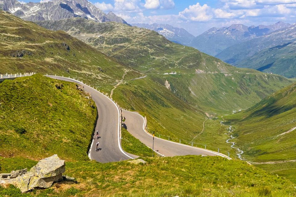 Cyclists climbing Furkapass Swiss alps valley and mountain peaks on marmot tours raid dolomites cycling challenge