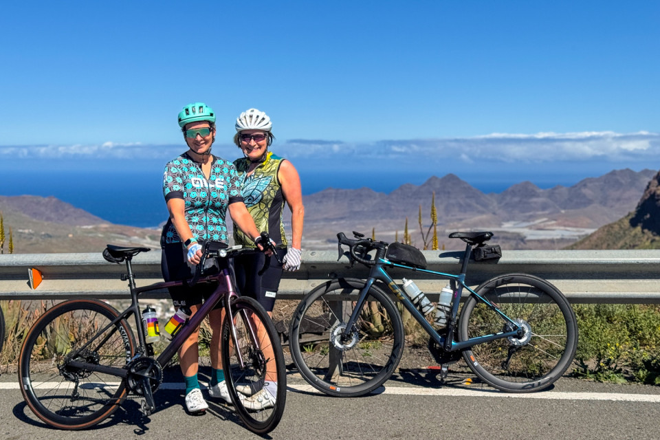 pair of cyclists pose while resting with Atlantic Ocean backdrop on Gran Canaria cycling holiday with marmot tours