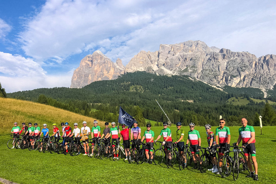 Group of cyclists post for photo in front of Italian Dolomites backdrop on Marmot Tours guided road cycling holiday