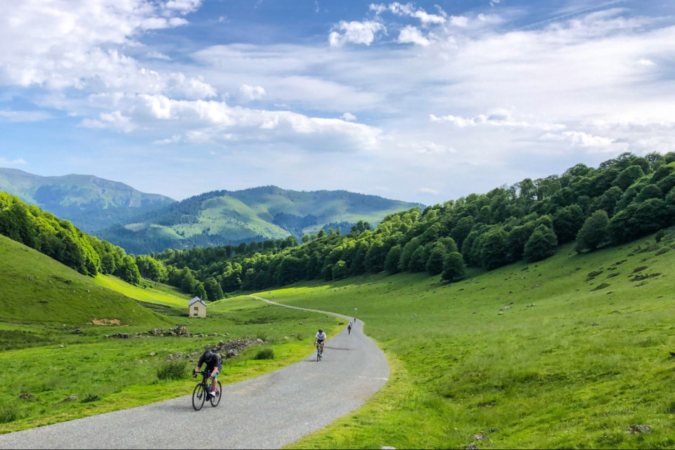 cyclists climbing col d'aspin through green pastures on raid pyrenees with marmot tours