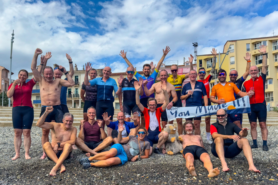 group of cyclists celebrate on beach at cerebra at finish line of raid pyrenees with marmot tours
