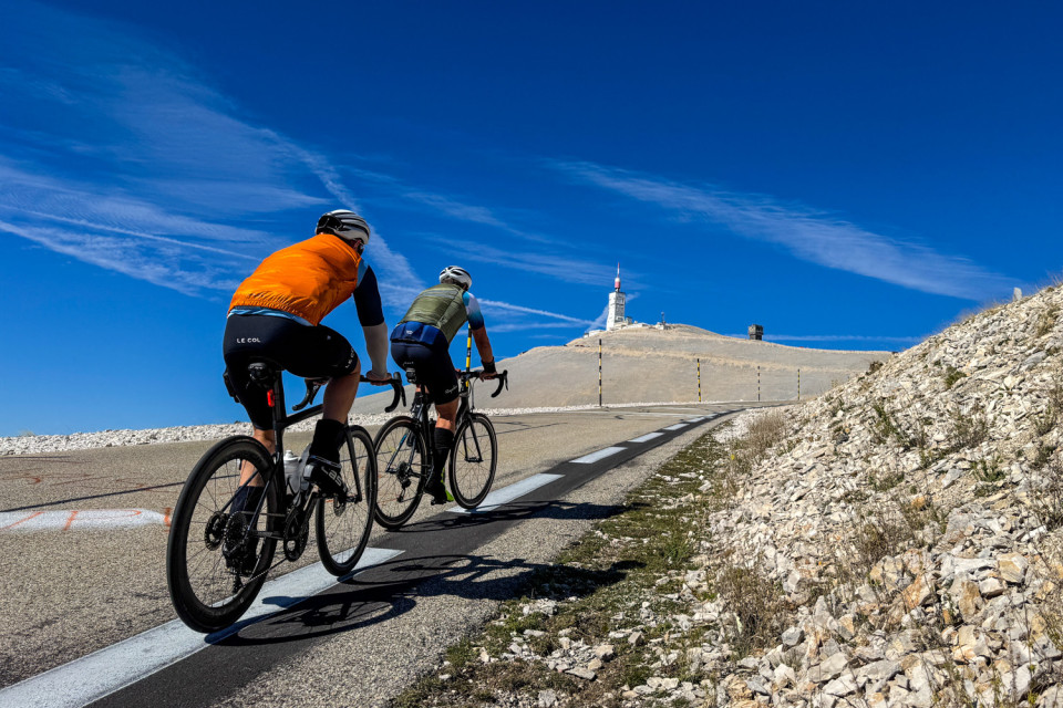 pair of cyclists climb mont Ventoux with limestone landscape surrounding and weather beacon summit in distance on marmot tours club des cingles cycling challenge
