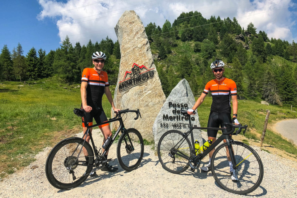 pair of cyclists pose at passo dello Mortirolo summit on marmot tours Italian dolomites cycling holiday