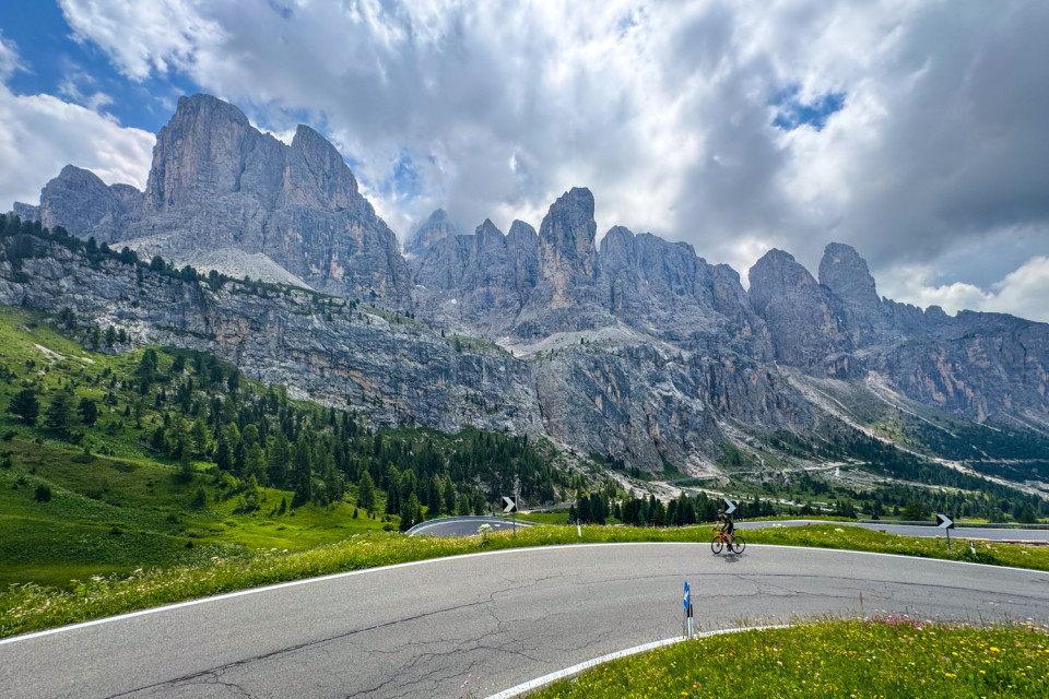 cyclist climbing passo gardena with towering limestone peaks in background on marmot tours cycling vacation in Italian dolomites