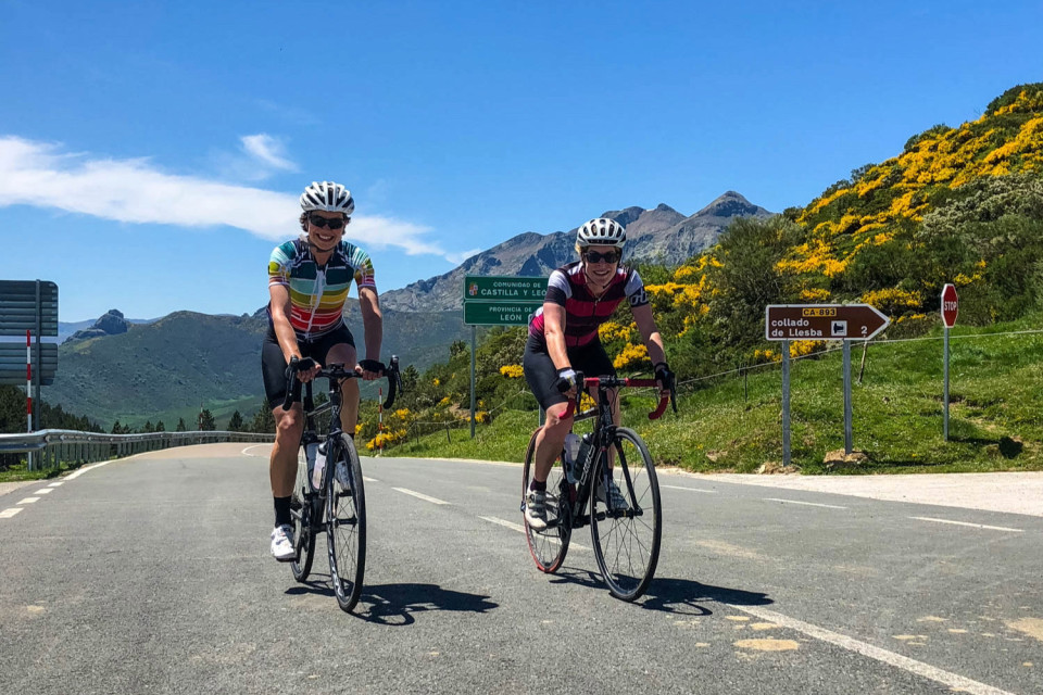 pair of female cyclists summiting climb in picos mountains on marmot tours road cycling holiday northern Spain