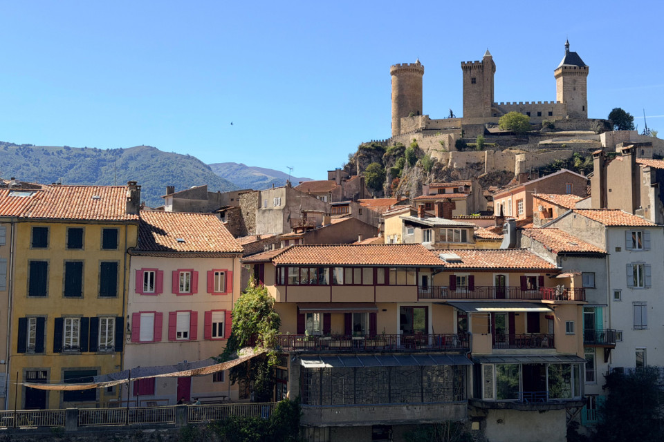 Foix castle on hilltop above medieval streets with Pyrenean foothills backdrop