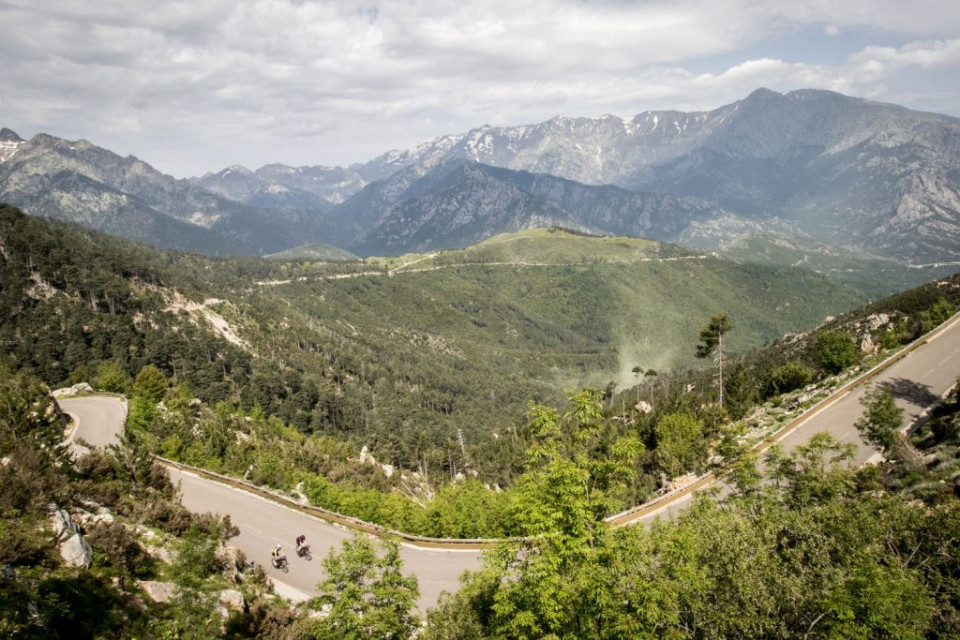 Pair of cyclists climbing Col de Sorba with mountainous backdrop on Raid Corsica with Marmot Tours road cycling holidays