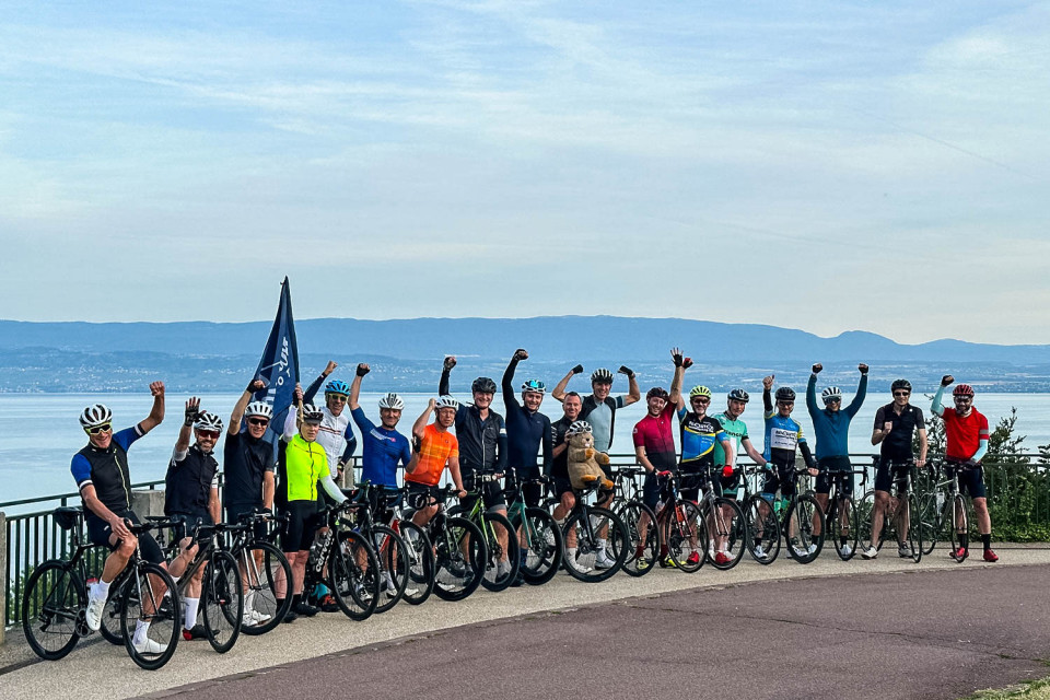Group of cyclists pose for photo on shire of Lake Geneva on Raid Dolomites cycling challenge with Marmot Tours