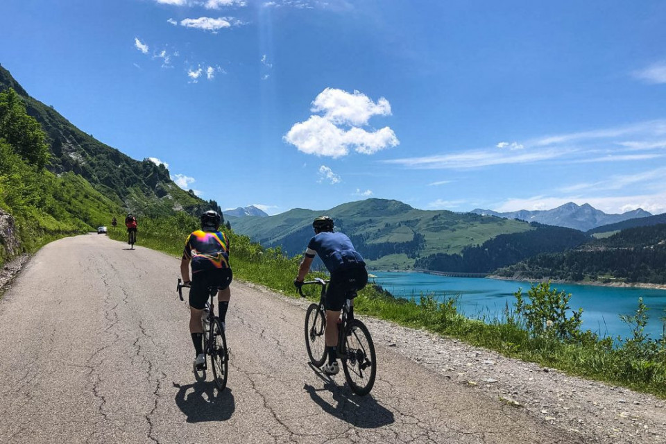 Cyclist climbing on Cormet de Roselend alongside Lac Roselend on Day 2 of Marmot Tours Raid Alpine cycling challenge French Alps
