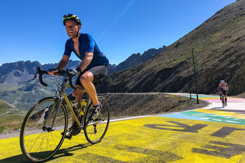 Happy cyclist summiting Col du Galibier on Day 4 ofMarmot Tours Raid Alpine cycling challenge French Alps