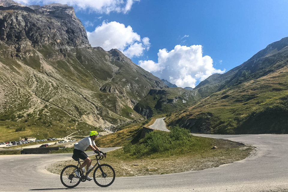 Cyclist climbs hairpin bend on col de l'iseran on marmot tours raid alpine cycling challenge