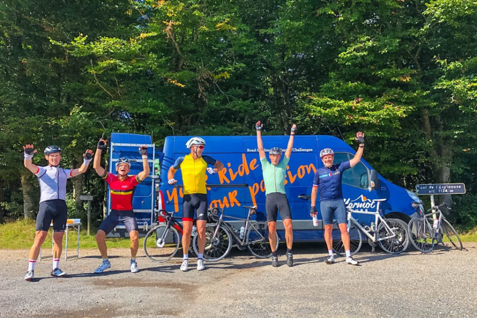 Group of cyclists jumping for joy at Col de L'Espinouse at finish of marmot Tours Raid Massif Central French cycling holiday