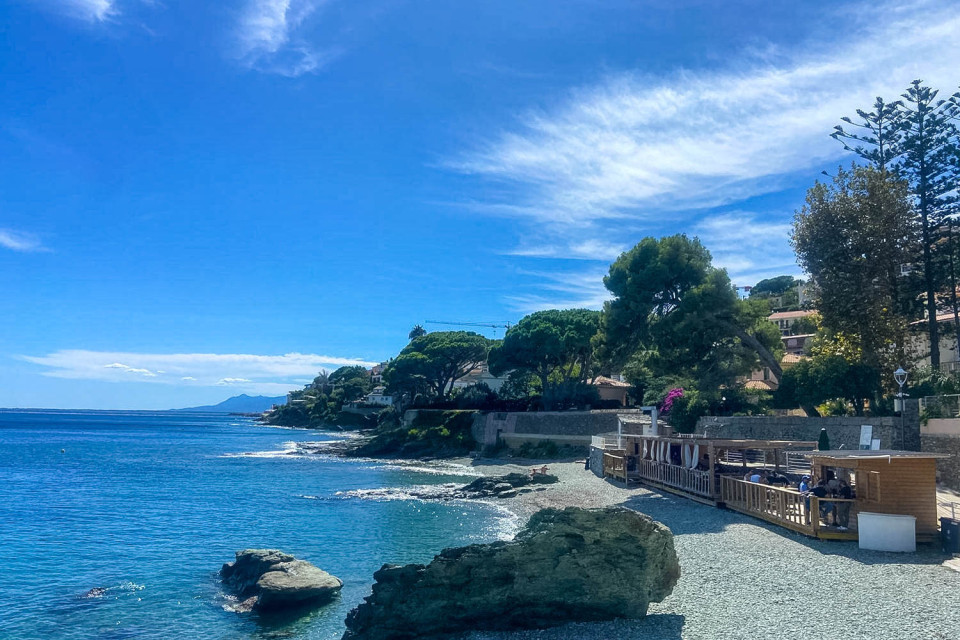 Sunny beach with taverna surrounded by trees at Pietranera on Marmot Tours road cycling holiday in Corsica