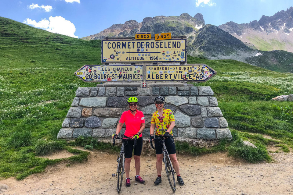 pair of cyclists pose at comet de Roselend col sign on marmot tours French alps cycling holiday