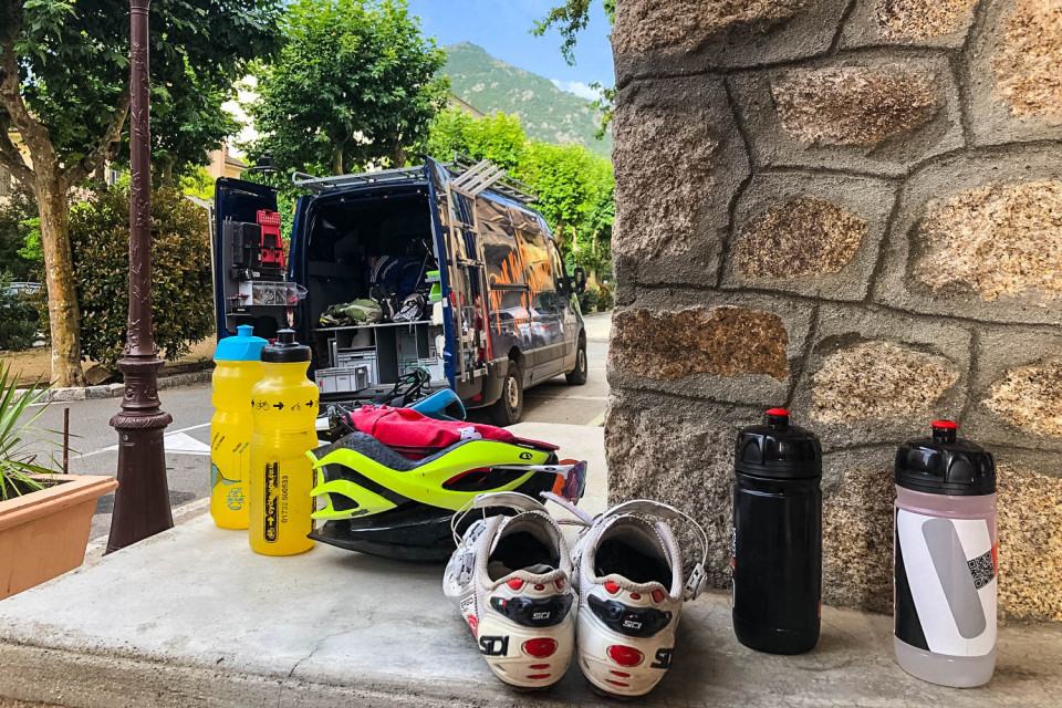 Cycling shoes helmet and bottles in from of Marmot Tours support vehicle on guided road cycling tour Corsica
