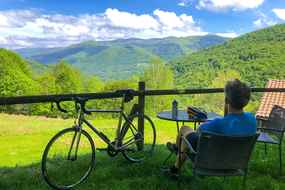 Cyclist seated at table admiring views of foothills of Pyrenees with Marmot Tours