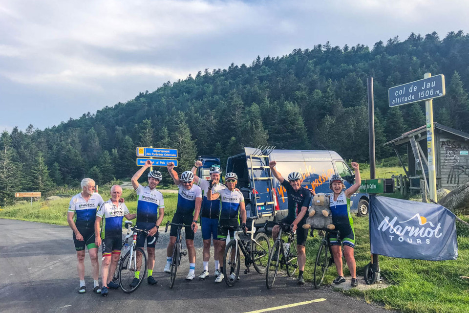 group of cyclists celebrate at col de jau on raid pyrenees with marmot tours van behind