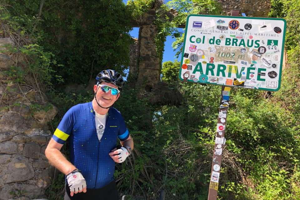 Cyclist smiling for photo at Col de Braus sign on Marmot Tours fully supported guided cycling tour Southern Alps