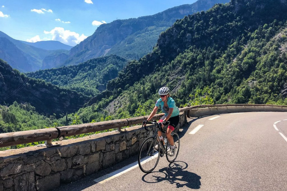 Female cyclist enjoying forested climb on guided cycling tour of Southern Alps with Marmot Tours