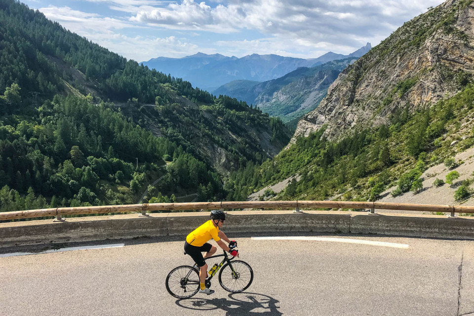 cyclist climbing col de la cajole in southern French alps with forested valley below on marmot tours cycling holiday