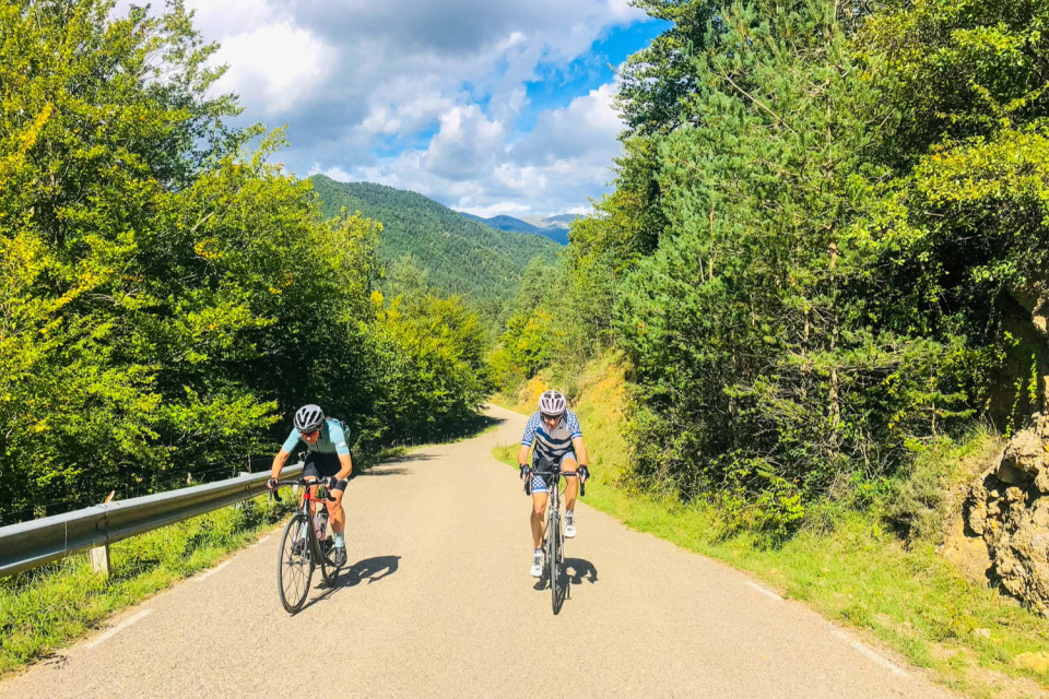 Pair of cyclists approaching camera on quiet road in Catalonia with Marmot Tours