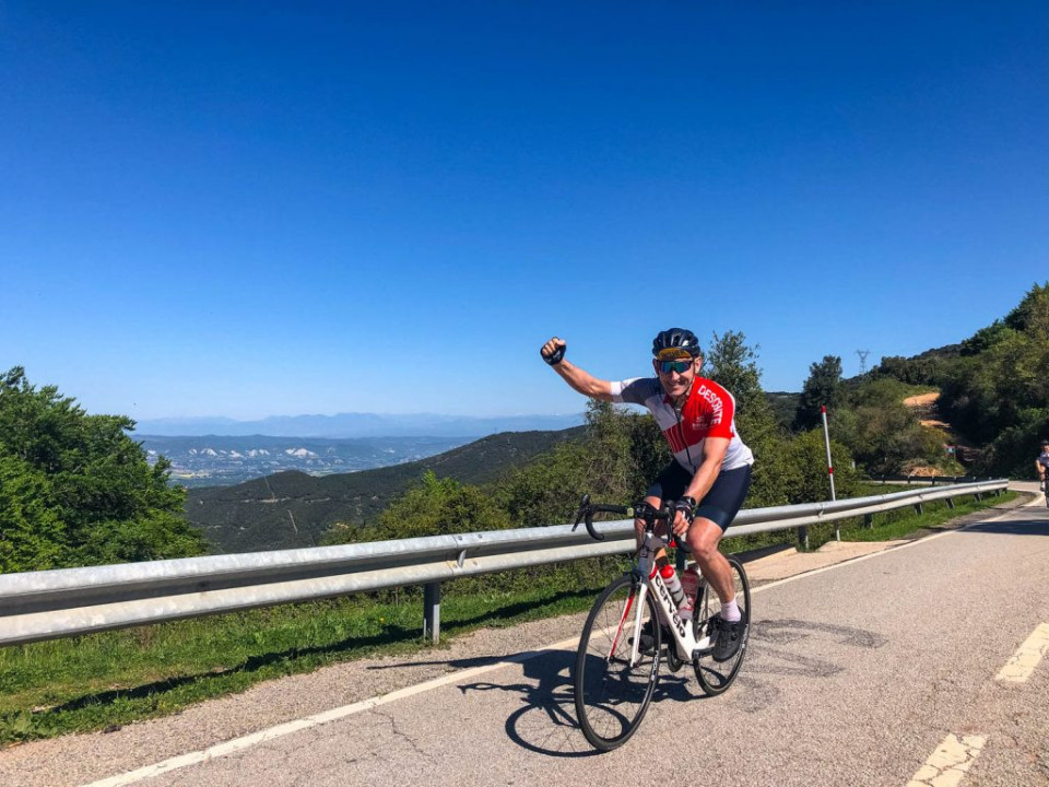 Cyclist fist pumping on climb in Catalonia on Marmot Tours guided road cycling holiday Girona Spain