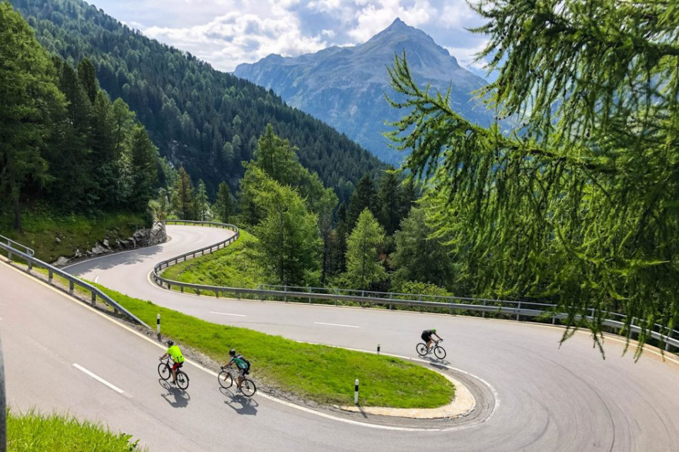 Trio of cyclists climbing hairpin ben on Passo del Maloja on Marmot Tours Raid Dolomites