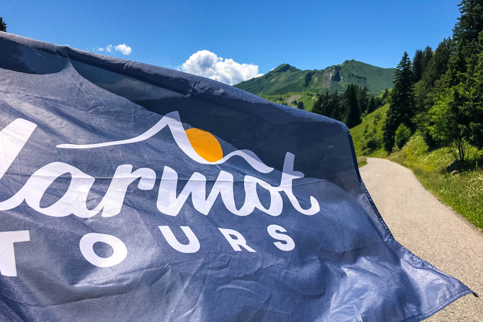 Marmot Tours road cycling holidays flag fluttering in breeze on sunny day on French Alps cycling holiday