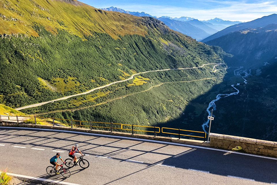 Pair of cyclists on furka grimsel pass on road crossing valley in Swiss alps on marmot tours raid dolomites cycling challenge