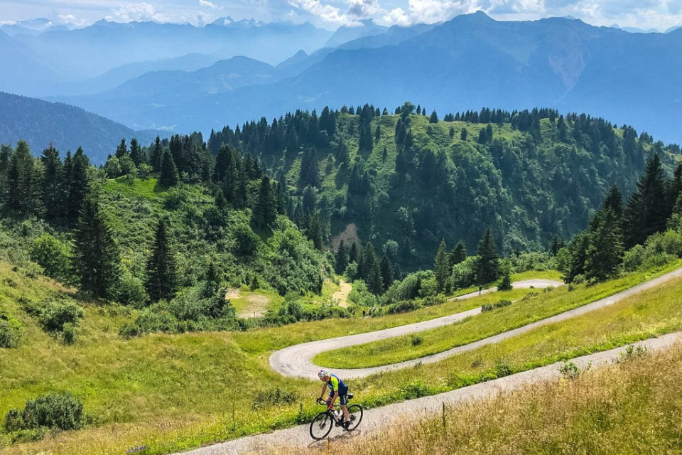 Cyclist and mountainous forest backdrop on Monte Zoncolan with Marmot Tours Raid Dolomites cycling challenge