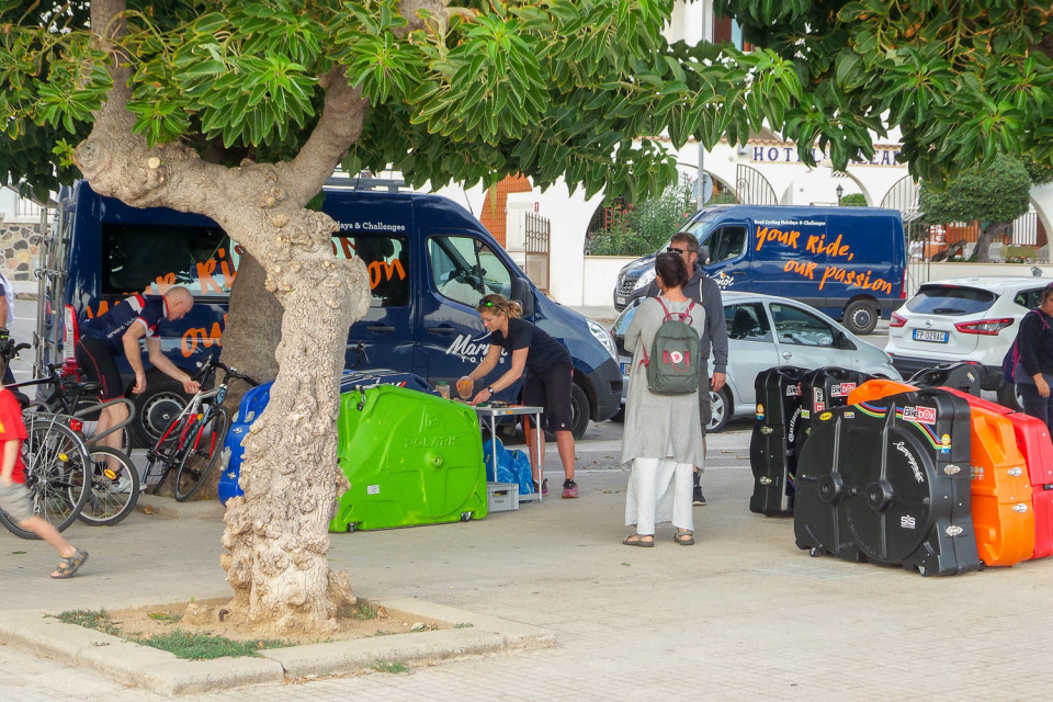 Group of cyclists and bike boxes packing Marmot Tours support vehicle on guided road cycling holiday Sardinia