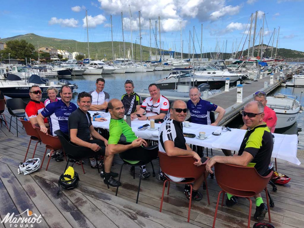 Cyclists enjoying dinner in harbour on guided road cycling holiday in Corsica with Marmot Tours