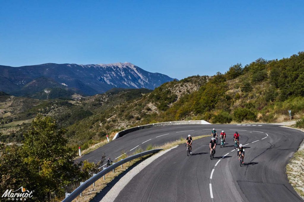 Group of cyclists climbing on hairpin bend Mont Ventoux background with Marmot Tours